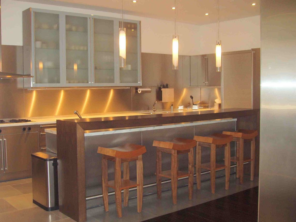 This is an example of a mid-sized modern u-shaped eat-in kitchen in New York with flat-panel cabinets, stainless steel cabinets, granite benchtops, metallic splashback, metal splashback, stainless steel appliances, porcelain floors, with island and beige floor.