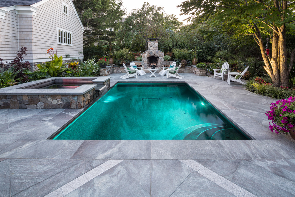 This is an example of a small traditional side yard rectangular lap pool in Portland Maine with a hot tub and natural stone pavers.