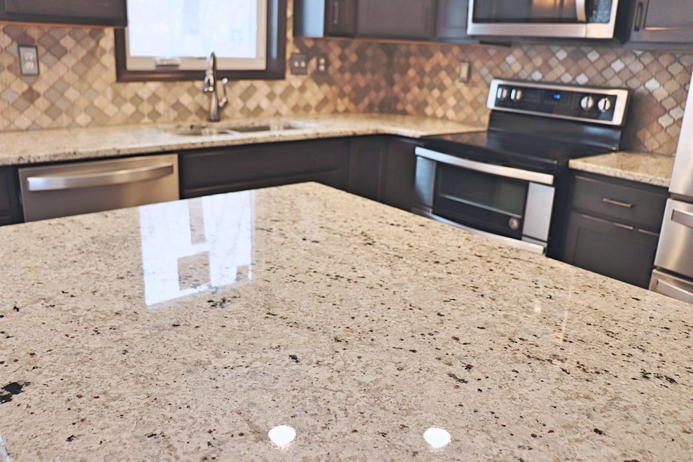 Small transitional u-shaped laminate floor and gray floor eat-in kitchen photo in Cedar Rapids with an undermount sink, recessed-panel cabinets, dark wood cabinets, granite countertops, gray backsplash, mosaic tile backsplash, stainless steel appliances, an island and white countertops