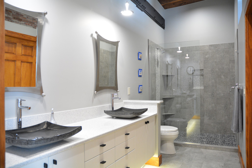 This is an example of a large contemporary master bathroom in Other with flat-panel cabinets, white cabinets, an open shower, a one-piece toilet, gray tile, porcelain tile, grey walls, porcelain floors, a vessel sink, engineered quartz benchtops, grey floor, an open shower and white benchtops.