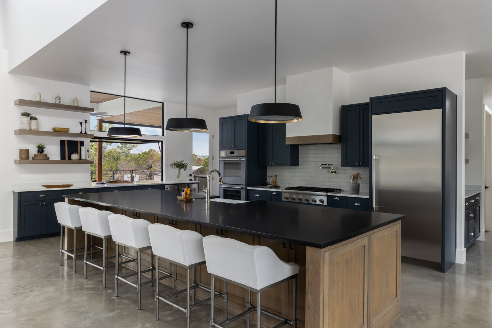 Design ideas for a scandinavian l-shaped open plan kitchen in Austin with a submerged sink, recessed-panel cabinets, blue cabinets, quartz worktops, white splashback, stainless steel appliances, concrete flooring, an island, grey floors and white worktops.