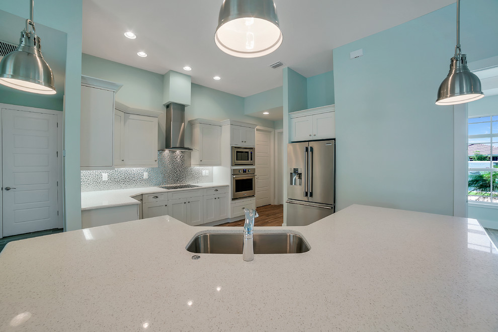 Example of a mid-sized transitional u-shaped open concept kitchen design with a drop-in sink, white cabinets, quartzite countertops, multicolored backsplash, mosaic tile backsplash, stainless steel appliances, an island and recessed-panel cabinets