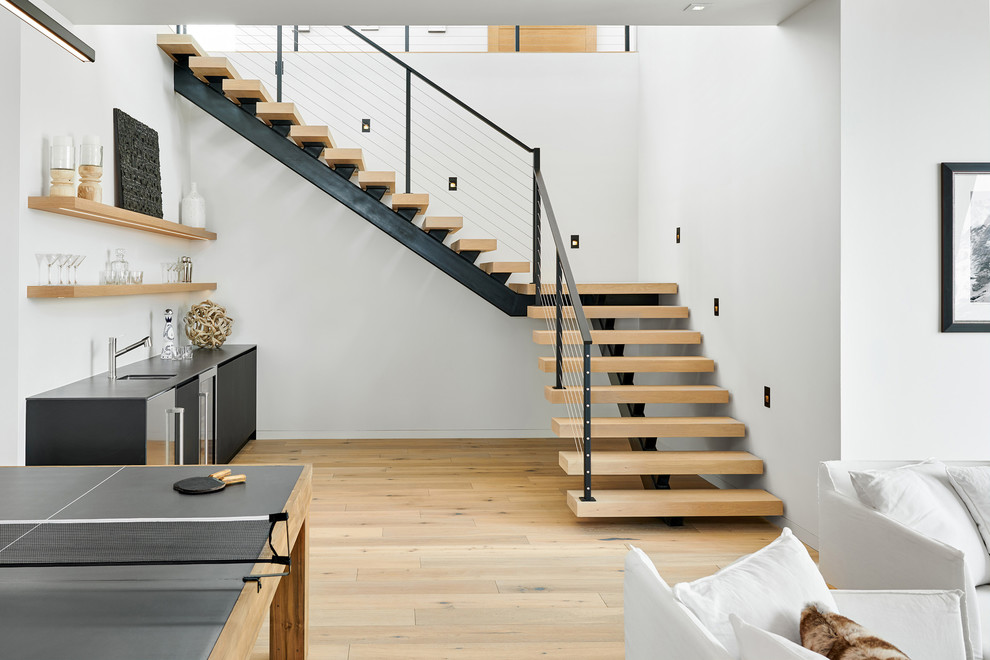 This is an example of a large contemporary wood floating staircase in Denver with open risers and metal railing.
