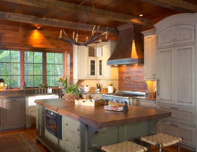 Large mountain style u-shaped medium tone wood floor enclosed kitchen photo with recessed-panel cabinets, light wood cabinets, an island, a farmhouse sink, wood countertops and brown backsplash