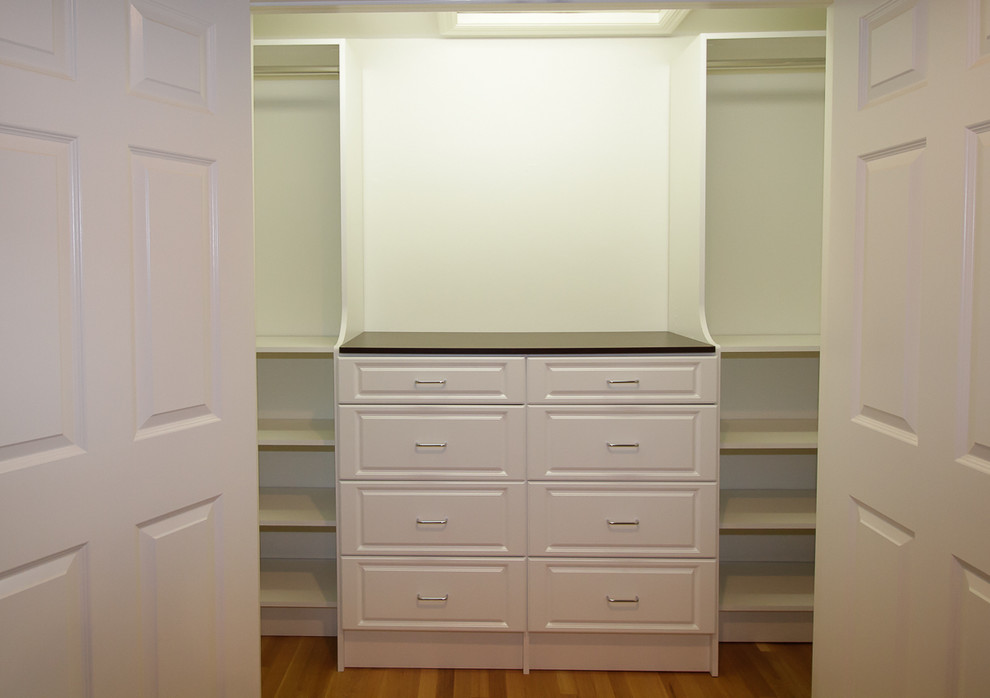 Mid-sized traditional gender-neutral built-in wardrobe in New York with raised-panel cabinets, white cabinets and medium hardwood floors.