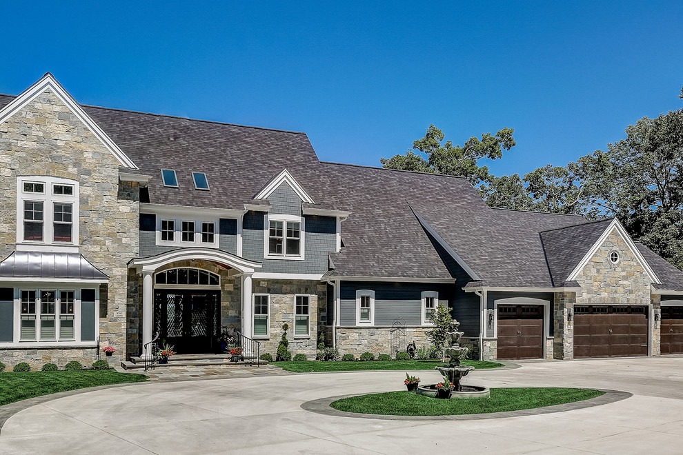 Inspiration for an expansive beach style two-storey grey house exterior in Milwaukee with stone veneer, a gable roof and a shingle roof.