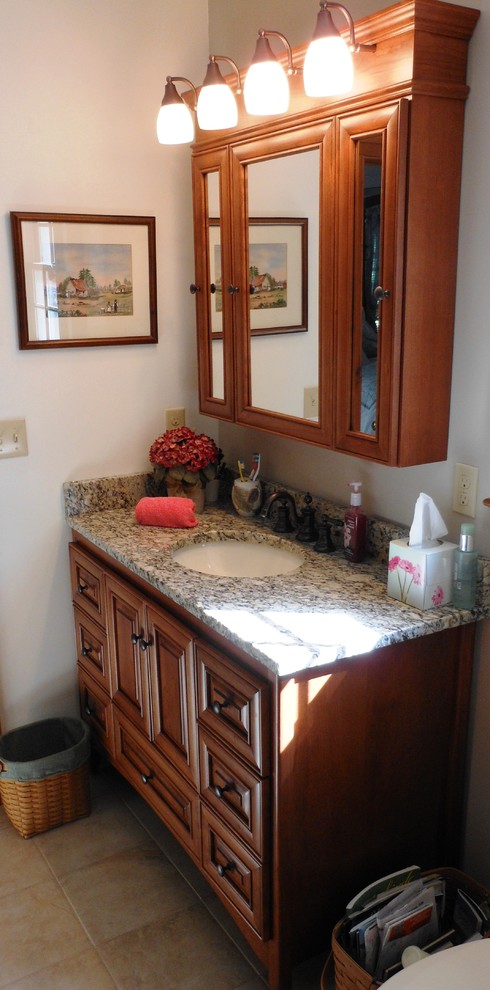 Bathroom - mid-sized rustic master beige tile and porcelain tile porcelain tile bathroom idea with raised-panel cabinets, medium tone wood cabinets, granite countertops and beige walls