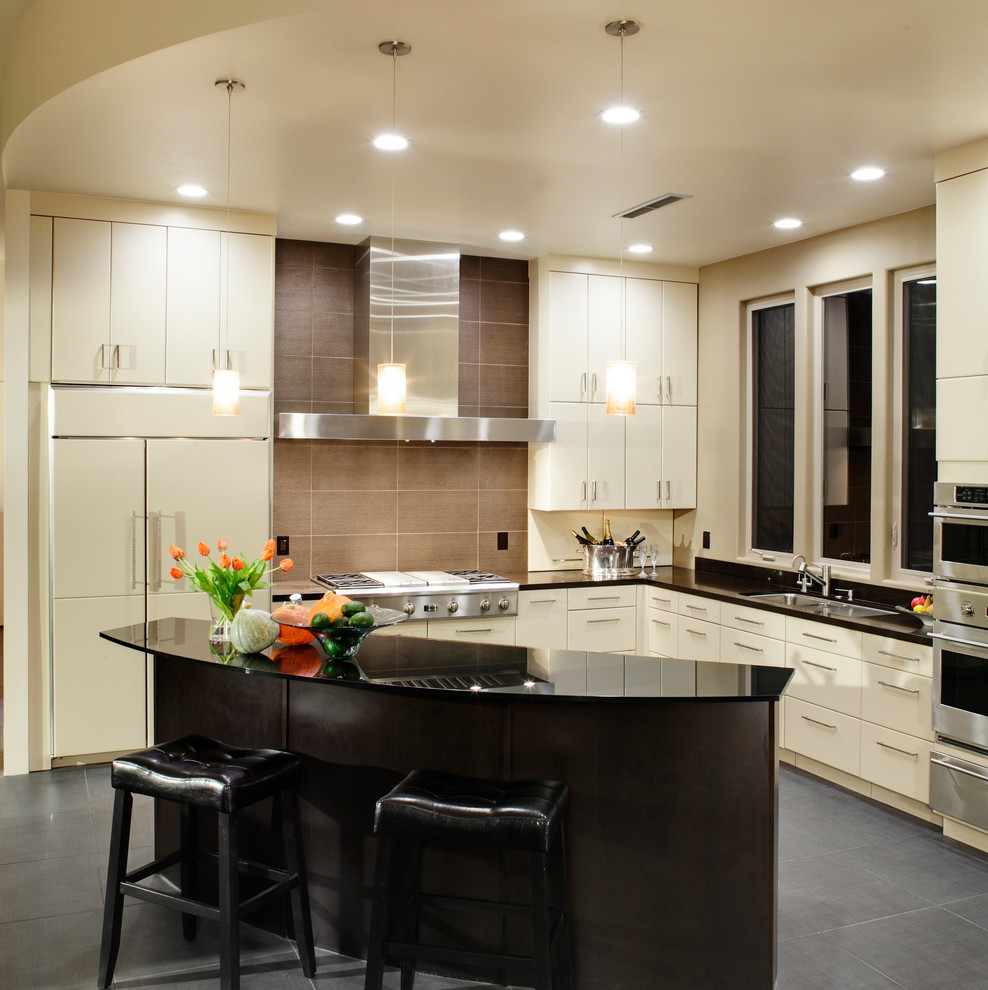 This is an example of a mid-sized contemporary l-shaped open plan kitchen in Sacramento with an undermount sink, flat-panel cabinets, white cabinets, glass benchtops, beige splashback, porcelain splashback, stainless steel appliances, porcelain floors and with island.