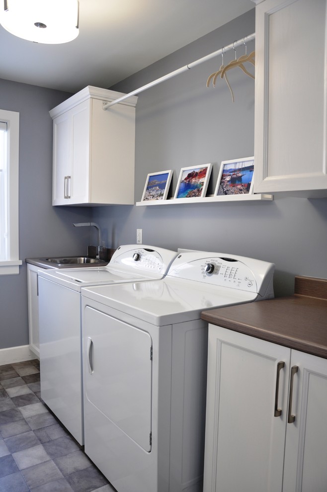 Mid-sized transitional galley utility room in Ottawa with a drop-in sink, shaker cabinets, white cabinets, laminate benchtops, grey walls, linoleum floors and a side-by-side washer and dryer.
