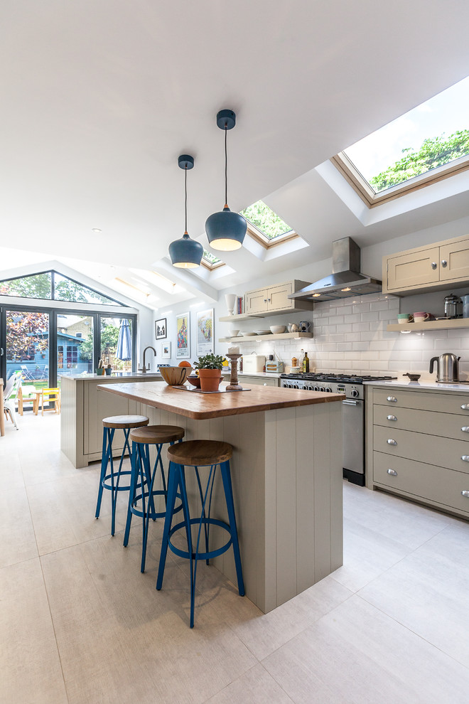 Photo of a country kitchen in Other with flat-panel cabinets, grey cabinets, white splashback, subway tile splashback, stainless steel appliances, light hardwood floors and with island.