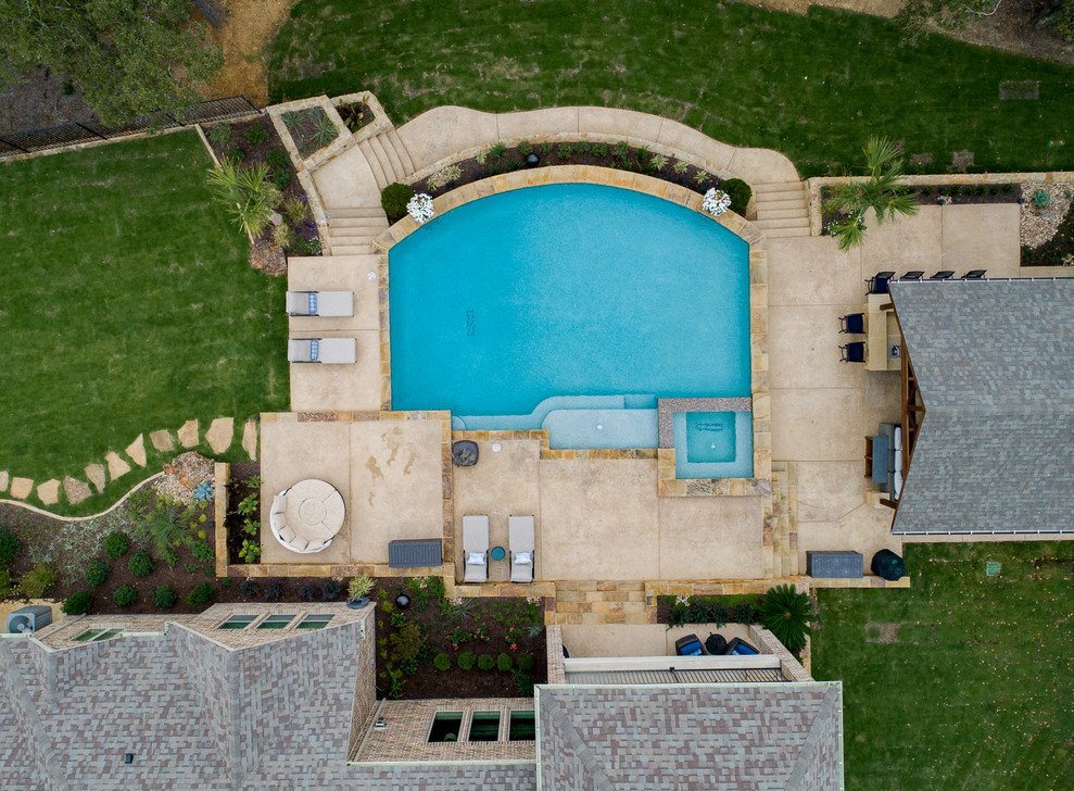 Inspiration for a large country backyard custom-shaped pool in Dallas with a hot tub and stamped concrete.