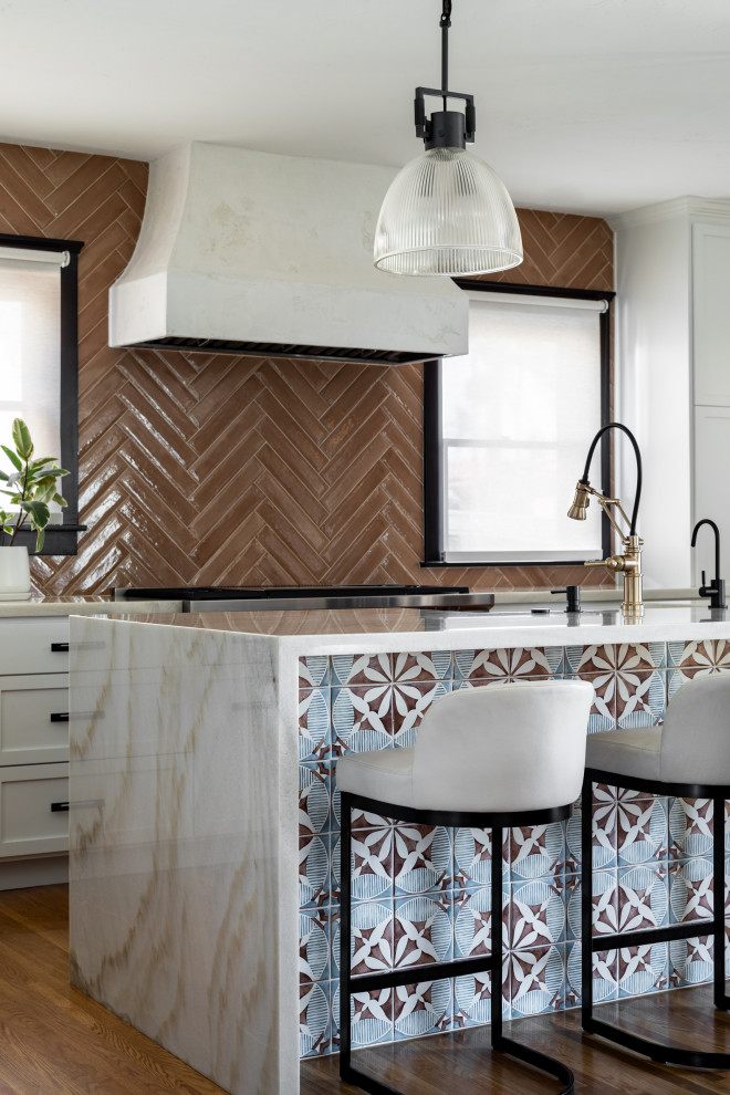 Inspiration for a mid-sized mediterranean l-shaped medium tone wood floor and brown floor eat-in kitchen remodel in San Diego with a farmhouse sink, shaker cabinets, white cabinets, quartzite countertops, pink backsplash, porcelain backsplash, stainless steel appliances, an island and white countertops