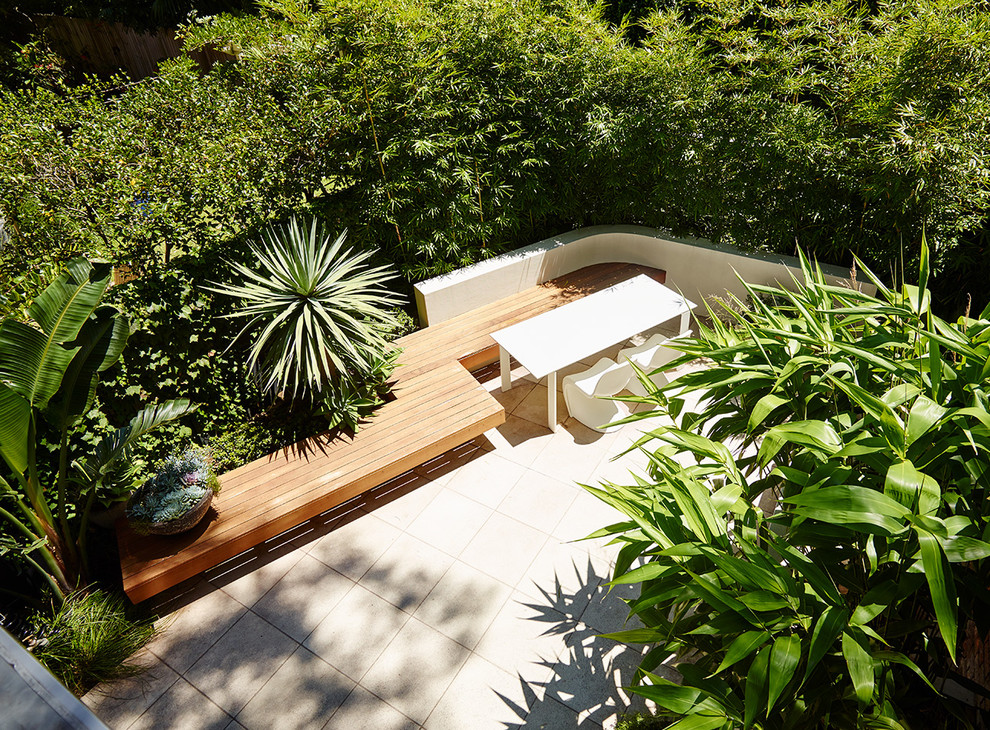 Small contemporary backyard formal garden in Sydney with natural stone pavers for summer.