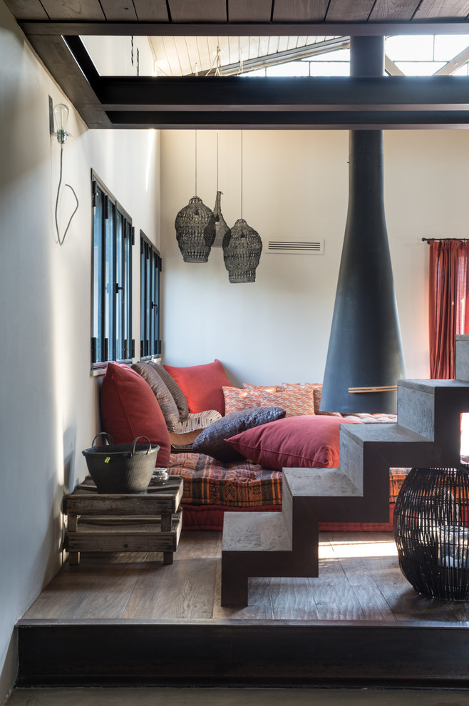 Photo of an industrial loft-style family room in Rome with a hanging fireplace, no tv and grey floor.