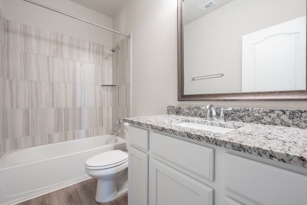 Inspiration for a medium sized family bathroom in Austin with shaker cabinets, white cabinets, an alcove bath, a shower/bath combination, a one-piece toilet, grey tiles, ceramic tiles, grey walls, vinyl flooring, a submerged sink, granite worktops, beige floors, a shower curtain, grey worktops, a single sink and a built in vanity unit.