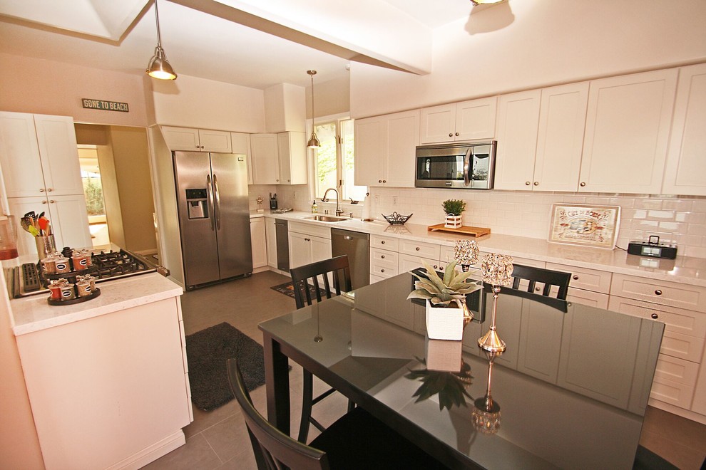 Example of a transitional galley eat-in kitchen design in Orange County with a single-bowl sink, shaker cabinets, white cabinets, white backsplash, subway tile backsplash and stainless steel appliances
