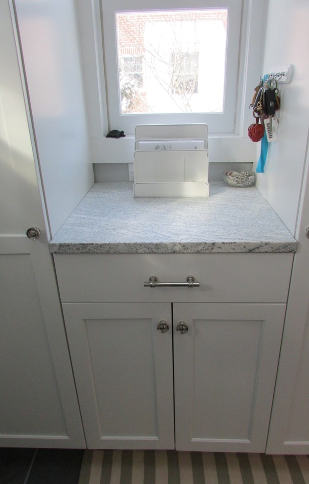 Example of a transitional slate floor eat-in kitchen design in New York with a farmhouse sink, recessed-panel cabinets, white cabinets and paneled appliances