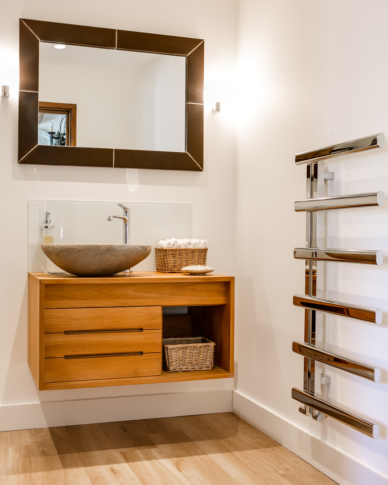 Contemporary bathroom in Gloucestershire with a vessel sink, flat-panel cabinets, medium wood cabinets, wood benchtops, white walls, light hardwood floors and brown benchtops.