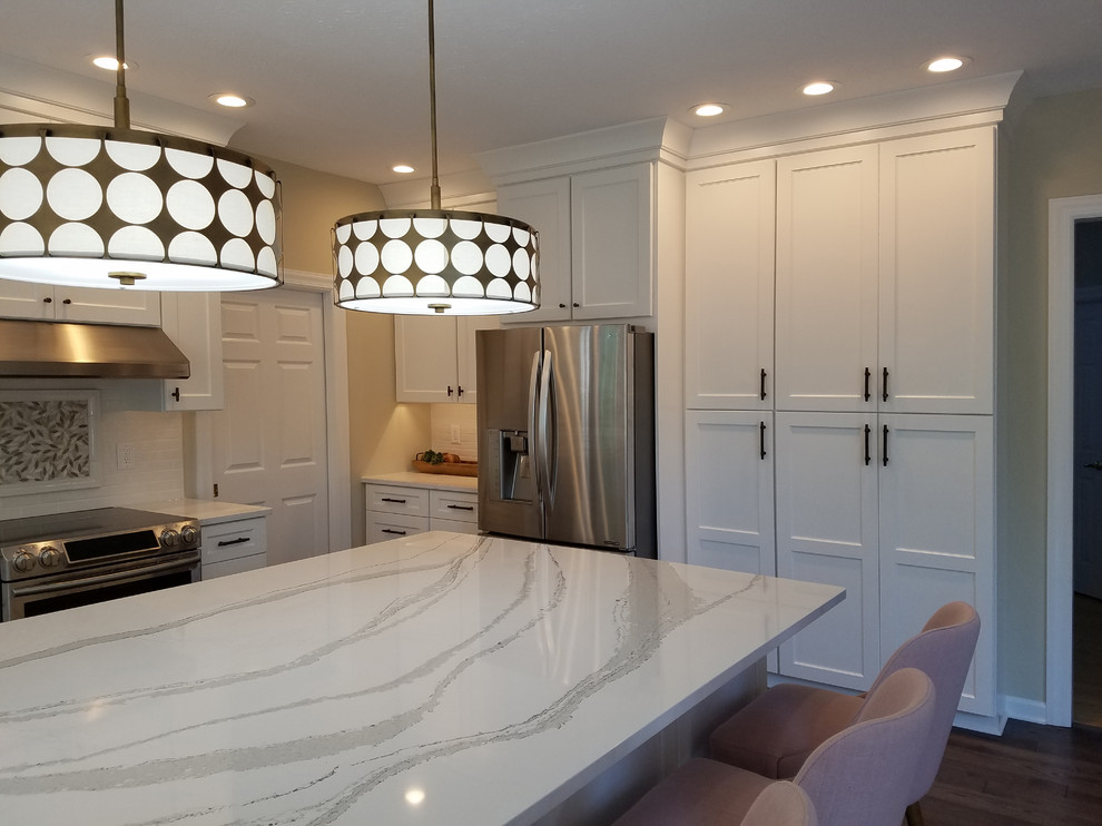 Eat-in kitchen - large transitional u-shaped medium tone wood floor and gray floor eat-in kitchen idea with shaker cabinets, white cabinets, quartz countertops, white backsplash, subway tile backsplash, stainless steel appliances, an island, white countertops and a farmhouse sink