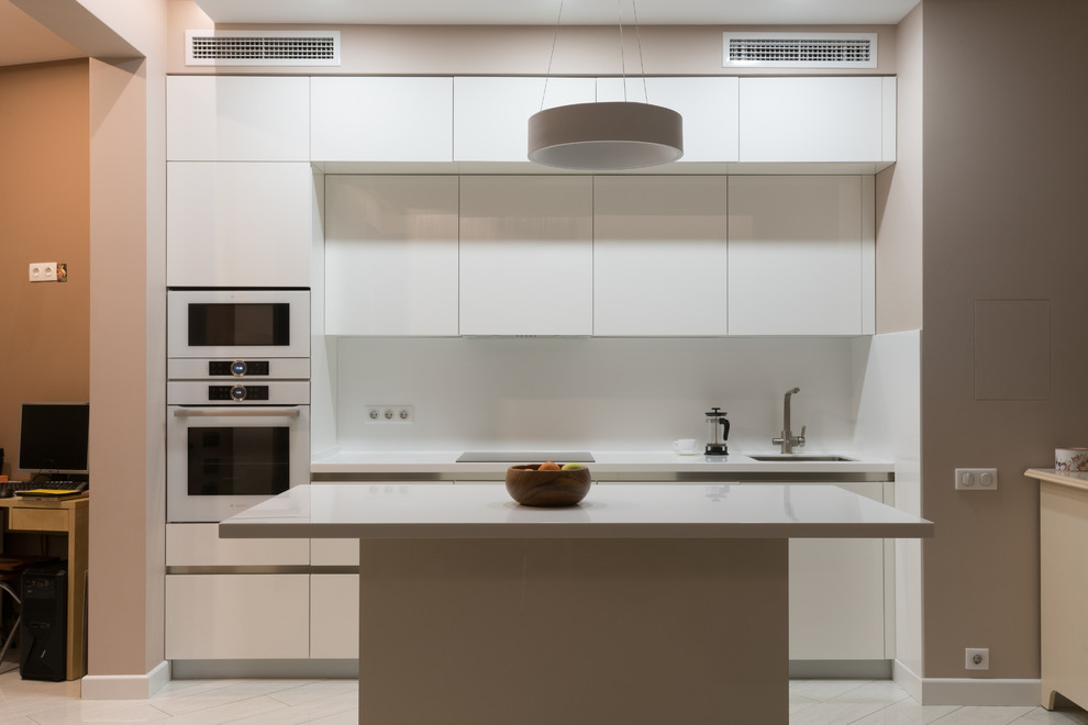 Mid-sized contemporary single-wall separate kitchen in Moscow with an integrated sink, flat-panel cabinets, white cabinets, solid surface benchtops, white splashback, glass sheet splashback, white appliances, ceramic floors, with island, white floor and white benchtop.