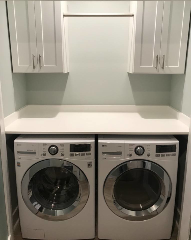 Photo of a mid-sized traditional single-wall dedicated laundry room in Jacksonville with shaker cabinets, white cabinets, beige walls, porcelain floors, a side-by-side washer and dryer, black floor and white benchtop.