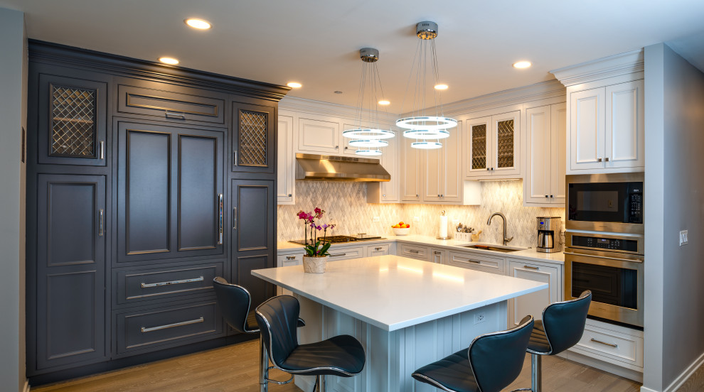 Example of a mid-sized transitional l-shaped marble floor eat-in kitchen design in Chicago with a single-bowl sink, beaded inset cabinets, white cabinets, quartz countertops, gray backsplash, marble backsplash, stainless steel appliances, an island and white countertops