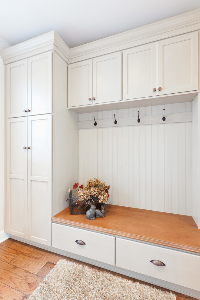 Inspiration for a mid-sized traditional single-wall dedicated laundry room in Atlanta with recessed-panel cabinets, white cabinets, wood benchtops, white walls, medium hardwood floors, a side-by-side washer and dryer, brown floor and brown benchtop.