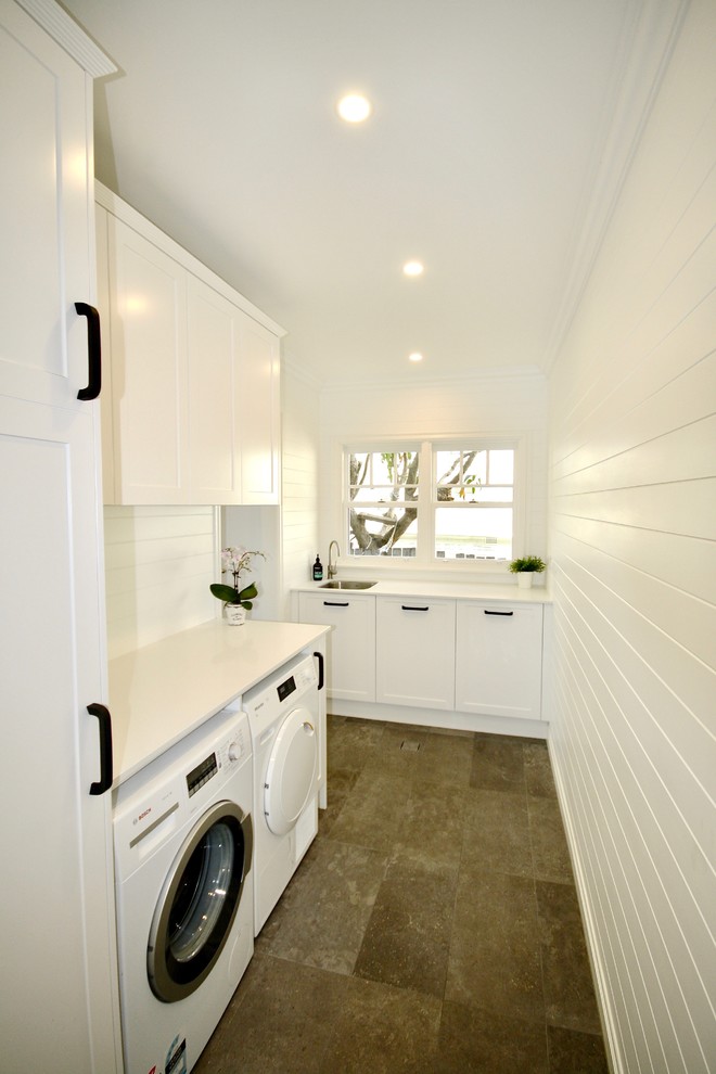 Photo of a mid-sized transitional u-shaped dedicated laundry room in Sydney with an undermount sink, shaker cabinets, white cabinets, quartz benchtops, white walls, porcelain floors, a side-by-side washer and dryer and brown floor.