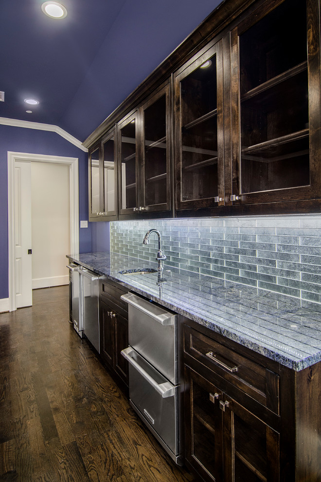 Large transitional single-wall wet bar in Dallas with an undermount sink, recessed-panel cabinets, dark wood cabinets, granite benchtops, multi-coloured splashback, metal splashback, dark hardwood floors and blue benchtop.