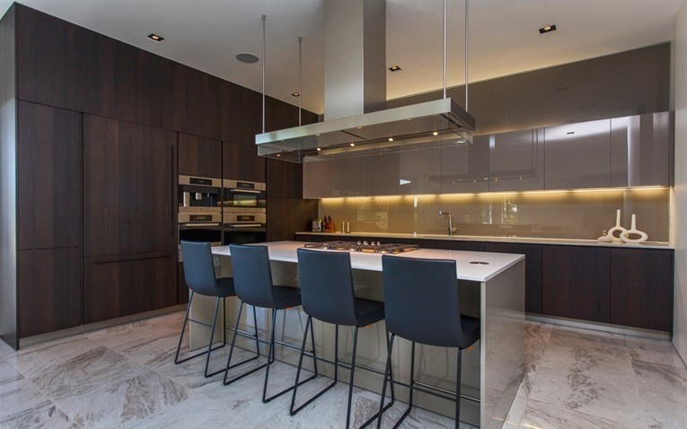 Photo of a large contemporary u-shaped eat-in kitchen in Other with an integrated sink, flat-panel cabinets, dark wood cabinets, quartzite benchtops, grey splashback, glass sheet splashback, marble floors, with island and panelled appliances.