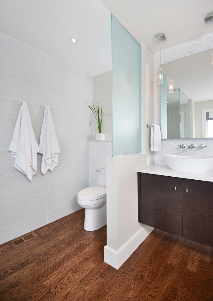 Photo of a modern master bathroom in Ottawa with a vessel sink, flat-panel cabinets, dark wood cabinets, engineered quartz benchtops, a freestanding tub, a curbless shower, a one-piece toilet, white tile, porcelain tile, grey walls and dark hardwood floors.