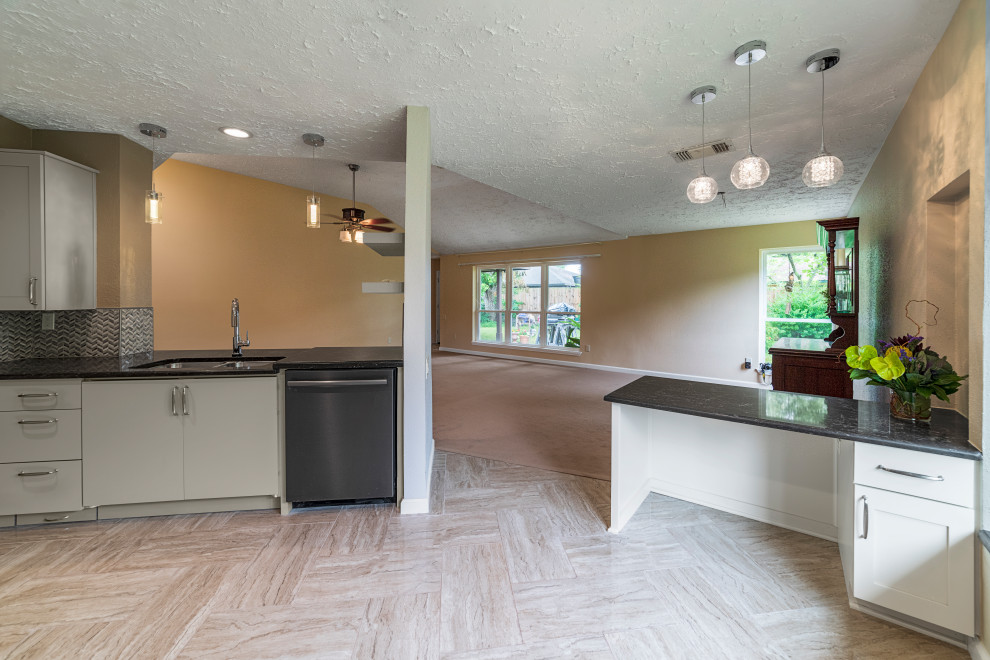 This is an example of a mid-sized transitional l-shaped separate kitchen in Houston with an undermount sink, shaker cabinets, grey cabinets, quartz benchtops, mosaic tile splashback, black appliances, porcelain floors, with island, beige floor and brown benchtop.