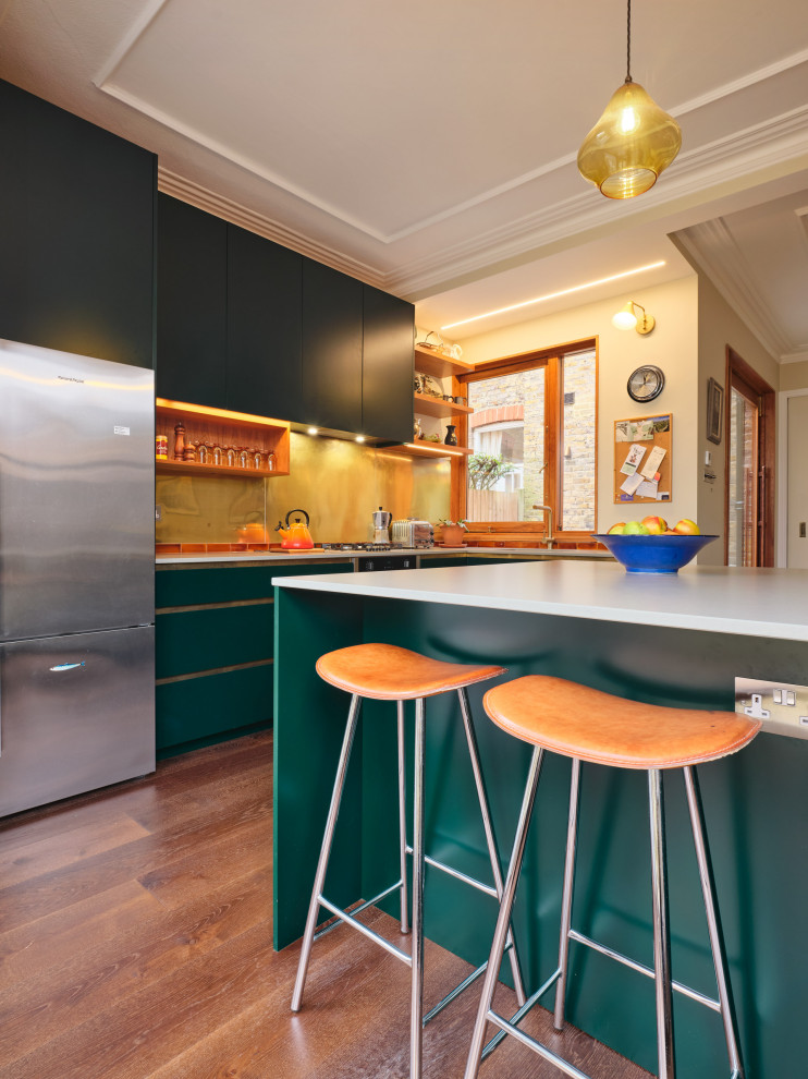 Foto de cocinas en L contemporánea de tamaño medio con armarios con paneles lisos, puertas de armario verdes, salpicadero metalizado, una isla y encimeras blancas