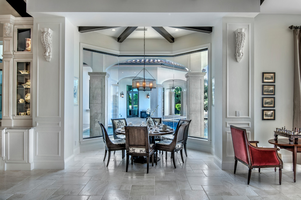 Photo of a large mediterranean kitchen/dining combo in Miami with white walls, travertine floors and beige floor.