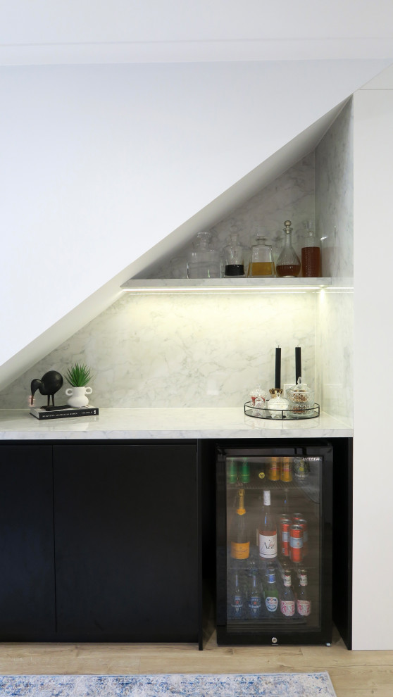 Small modern single-wall home bar in Brisbane with white cabinets, laminate benchtops, white splashback and black benchtop.