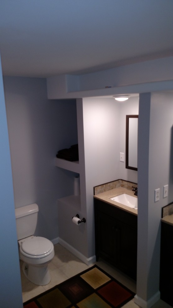 Example of a mid-sized transitional master porcelain tile and beige floor corner bathtub design with shaker cabinets, black cabinets, a two-piece toilet, gray walls, an undermount sink, laminate countertops, a hinged shower door and beige countertops