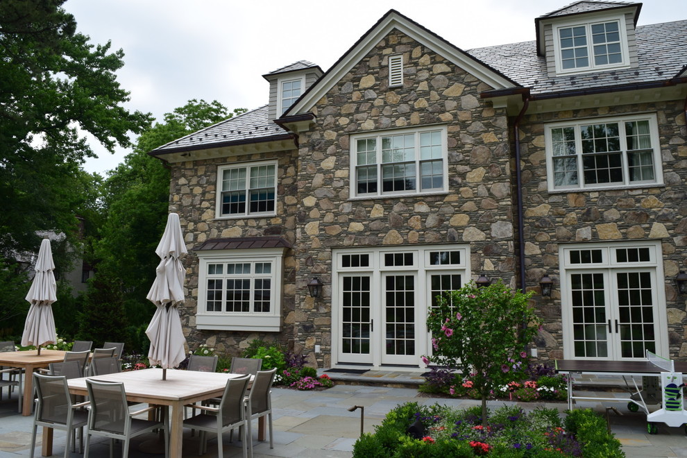 Inspiration for a large traditional two-storey beige exterior in New York with stone veneer and a gable roof.