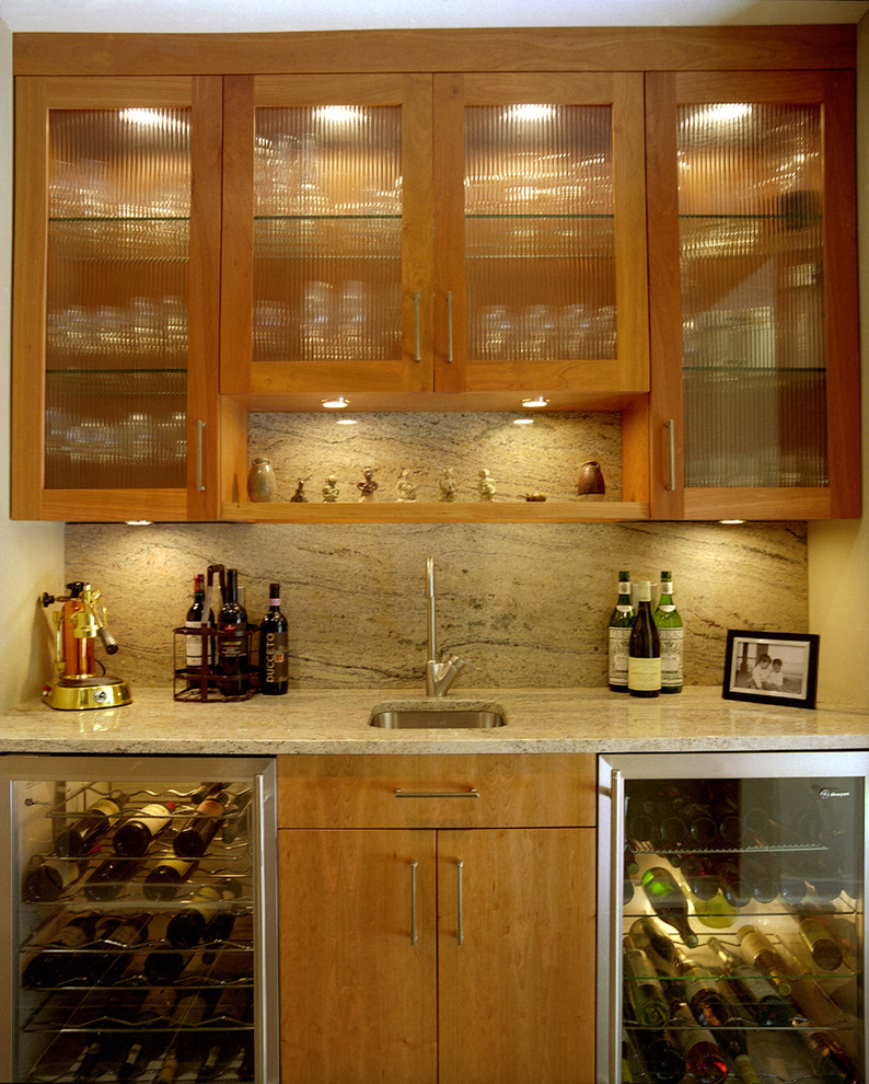 This is an example of a small contemporary single-wall wet bar in New York with an undermount sink, flat-panel cabinets, medium wood cabinets, granite benchtops and stone slab splashback.