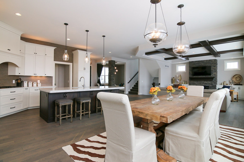 Example of a large transitional u-shaped medium tone wood floor and brown floor eat-in kitchen design with a drop-in sink, recessed-panel cabinets, white cabinets, marble countertops, beige backsplash, stone tile backsplash, stainless steel appliances and an island
