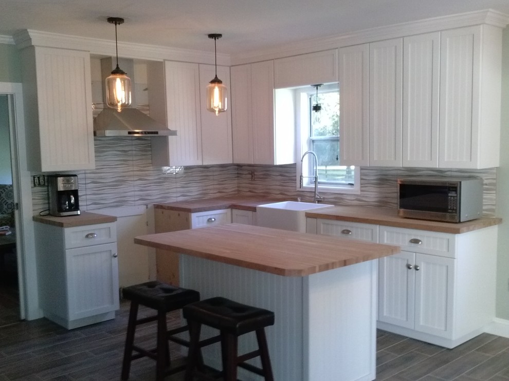 Design ideas for a mid-sized country l-shaped eat-in kitchen in Orlando with a farmhouse sink, beaded inset cabinets, white cabinets, wood benchtops, stainless steel appliances, ceramic floors, with island, multi-coloured splashback and cement tile splashback.