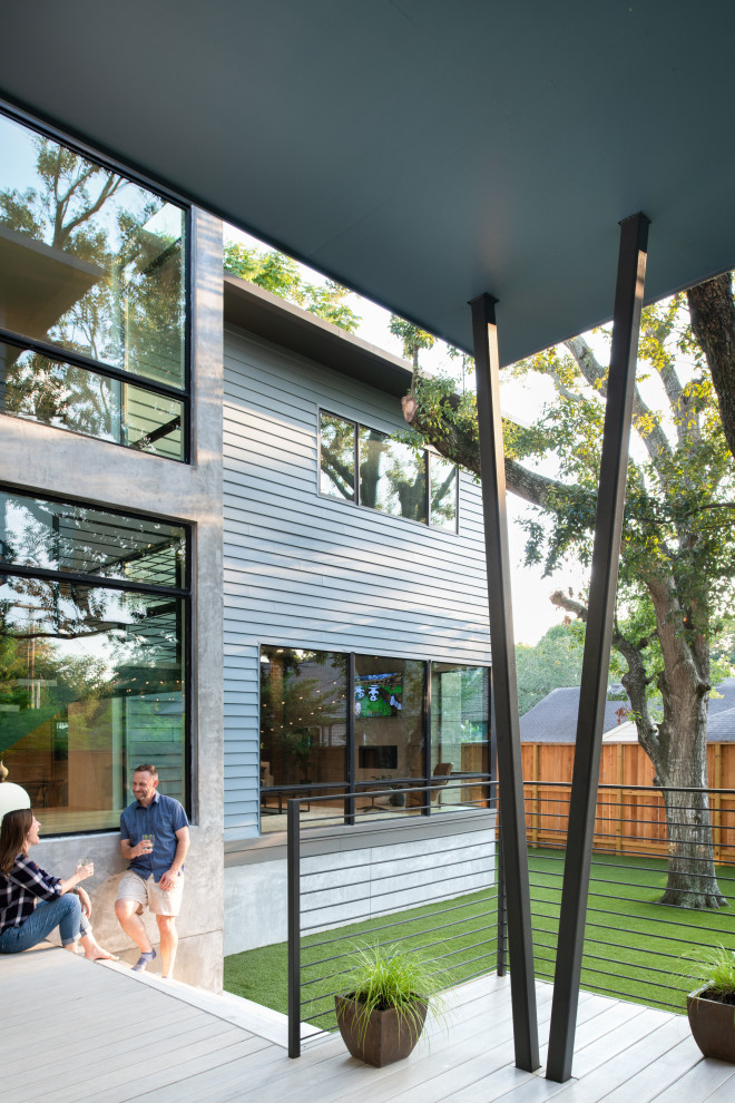 This is an example of a mid-sized midcentury two-storey blue house exterior in Houston with concrete fiberboard siding, a hip roof, a mixed roof, a brown roof and shingle siding.