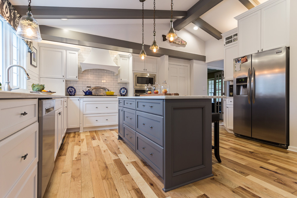 Enclosed kitchen - large transitional u-shaped medium tone wood floor and brown floor enclosed kitchen idea with an undermount sink, shaker cabinets, white cabinets, quartzite countertops, white backsplash, subway tile backsplash, stainless steel appliances and an island