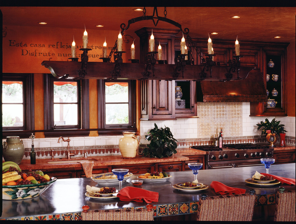 Photo of a country galley eat-in kitchen in San Diego with an undermount sink, raised-panel cabinets, distressed cabinets, granite benchtops, beige splashback, mosaic tile splashback and stainless steel appliances.