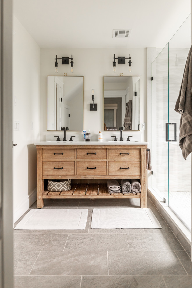 Photo of a mid-sized country master bathroom with furniture-like cabinets, light wood cabinets, an alcove tub, gray tile, ceramic tile, white walls, ceramic floors, an undermount sink, engineered quartz benchtops, grey floor, a hinged shower door, white benchtops, a double vanity, a freestanding vanity and an alcove shower.