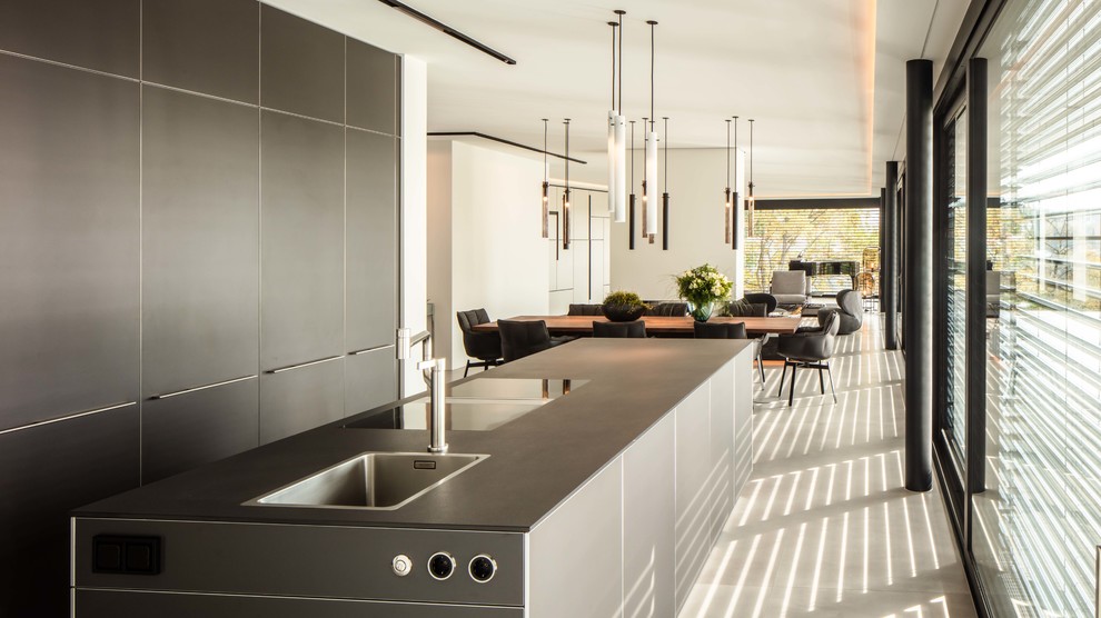 Design ideas for a contemporary open plan kitchen in Stuttgart with flat-panel cabinets, black cabinets, tile benchtops, with island and black benchtop.