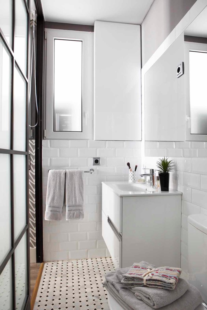 Design ideas for a contemporary bathroom in Madrid with white cabinets, white walls, white benchtops, flat-panel cabinets, white tile, subway tile, an integrated sink and multi-coloured floor.