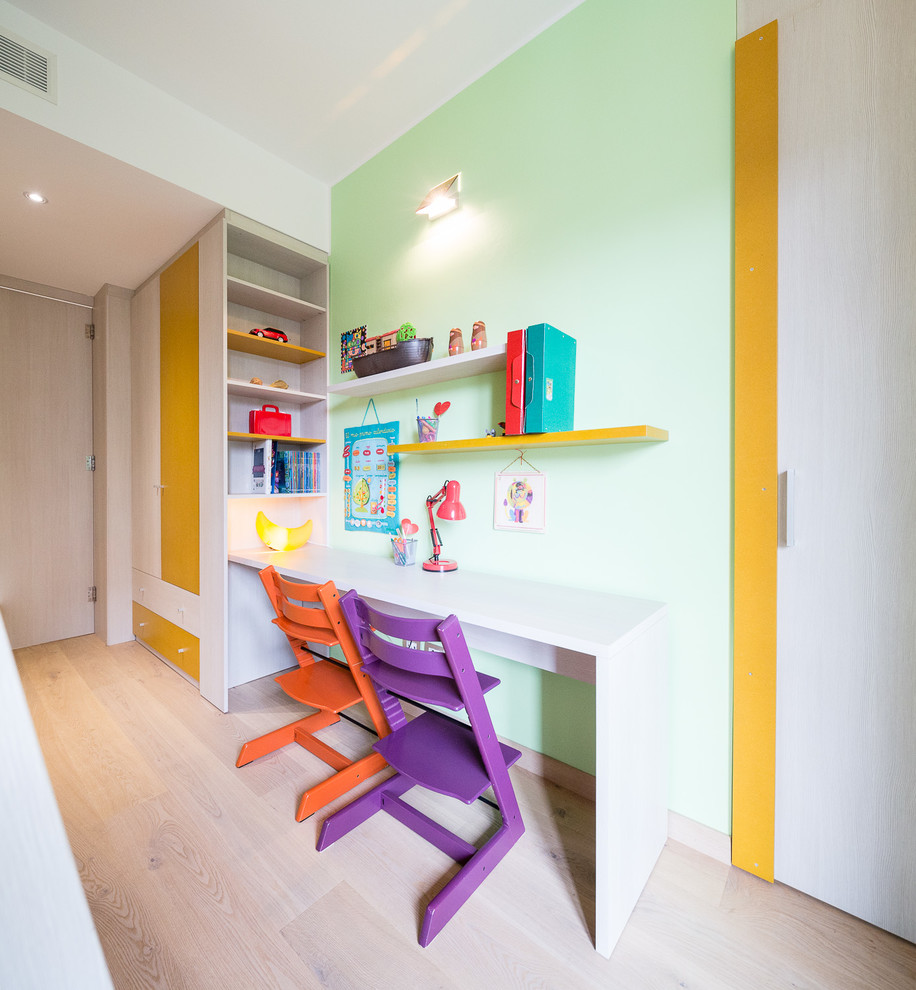 Design ideas for a mid-sized contemporary gender-neutral kids' study room for kids 4-10 years old in Milan with multi-coloured walls and light hardwood floors.
