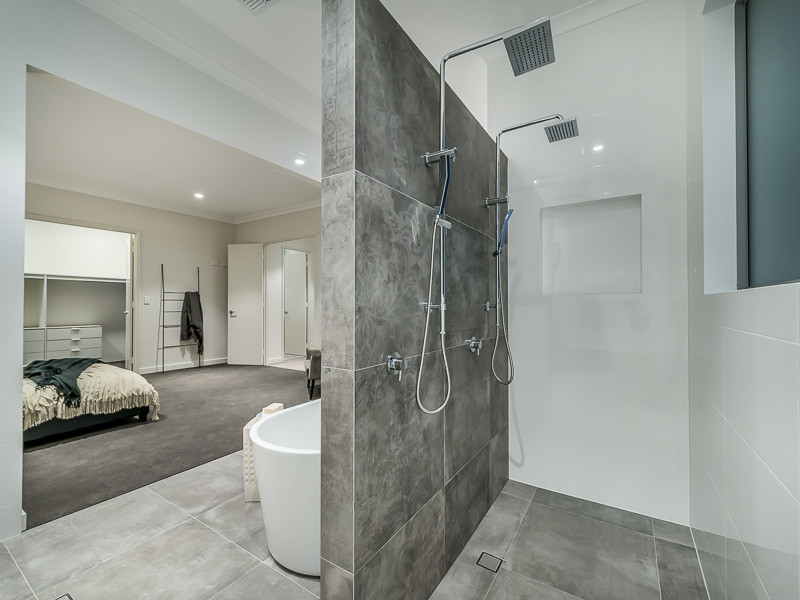 Inspiration for an expansive contemporary master bathroom in Perth with flat-panel cabinets, light wood cabinets, a freestanding tub, a double shower, a wall-mount toilet, white tile, porcelain tile, white walls, porcelain floors, a vessel sink, engineered quartz benchtops, grey floor and a hinged shower door.