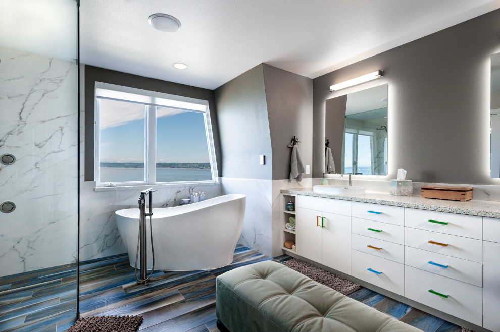 Photo of a large contemporary master bathroom in Seattle with flat-panel cabinets, white cabinets, a freestanding tub, a curbless shower, a two-piece toilet, white tile, stone slab, grey walls, wood-look tile, a vessel sink, engineered quartz benchtops, blue floor, a hinged shower door, beige benchtops, a shower seat, a double vanity and a built-in vanity.