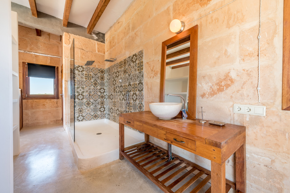 Photo of a mediterranean master bathroom in Palma de Mallorca with open cabinets, medium wood cabinets, an open shower, pink walls, a vessel sink, wood benchtops, beige floor and an open shower.